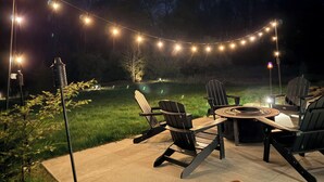 An outdoor patio with string lights, chairs, and a round table.