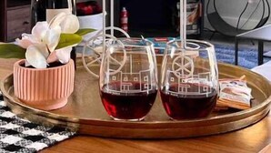 A cozy room with a fireplace, a wine bottle, and three glasses of red wine on a tray.