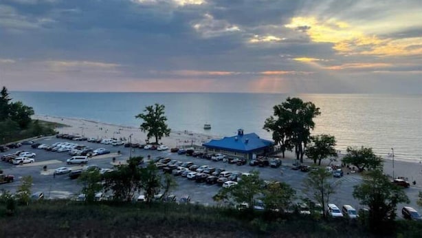 A coastal parking area with a building and trees, overlooking the sea.