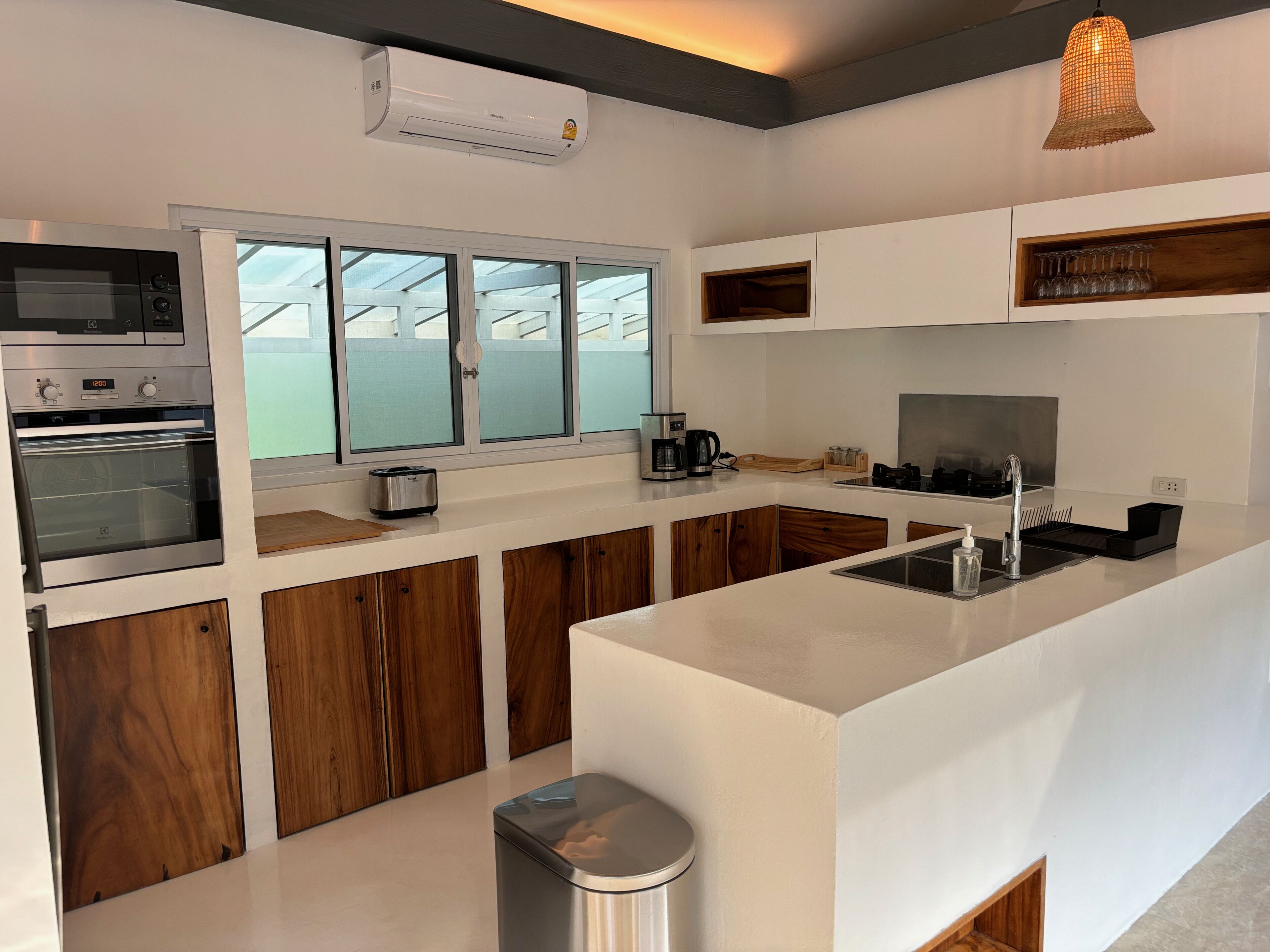 Una cocina moderna con horno empotrado, cafetera y pileta.