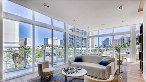 A spacious living room with large windows, a sofa, a coffee table, and a chair.