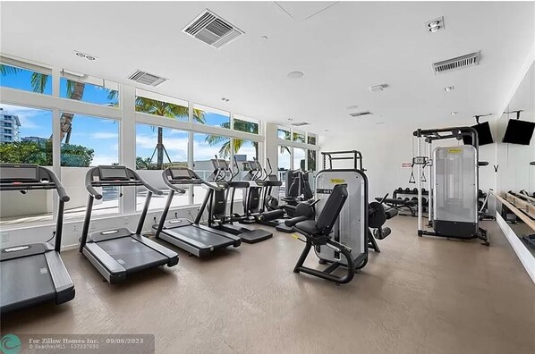 A gym with treadmills, weight machines, and a bench.