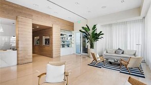 A modern lobby with a reception desk, seating area, and a large plant.