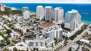 An aerial view of a coastal urban area with high-rise buildings, roads, and a beach.