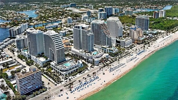 A coastal cityscape with high-rise hotels, a beach, and a marina.
