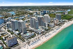 A coastal cityscape with high-rise hotels, a beach, and a marina.