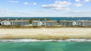 Un hôtel situé en bord de mer, composé de plusieurs bâtiments, avec une plage de sable et donnant sur l’océan.