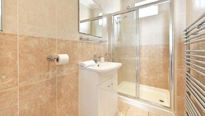 A bathroom with a glass shower enclosure, a sink, and a toilet. - Captivating 1-bed Apartment in London (London)