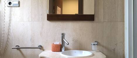 A bathroom with a white sink, a mirror, and a towel rack.