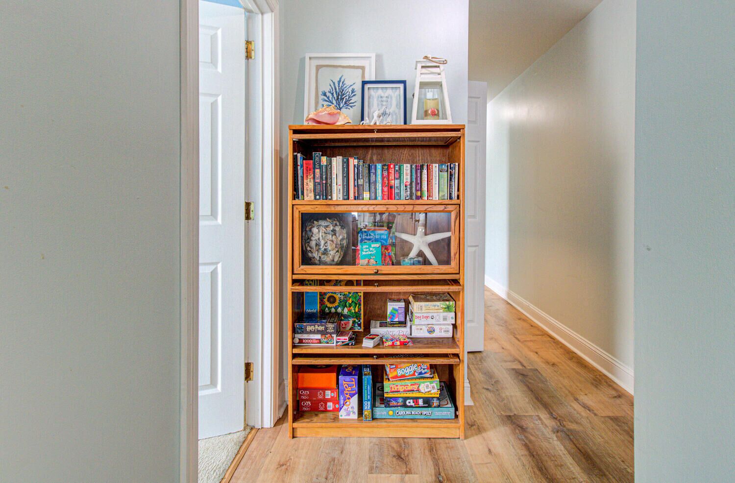 A hallway with a wooden bookshelf filled with books and board games.