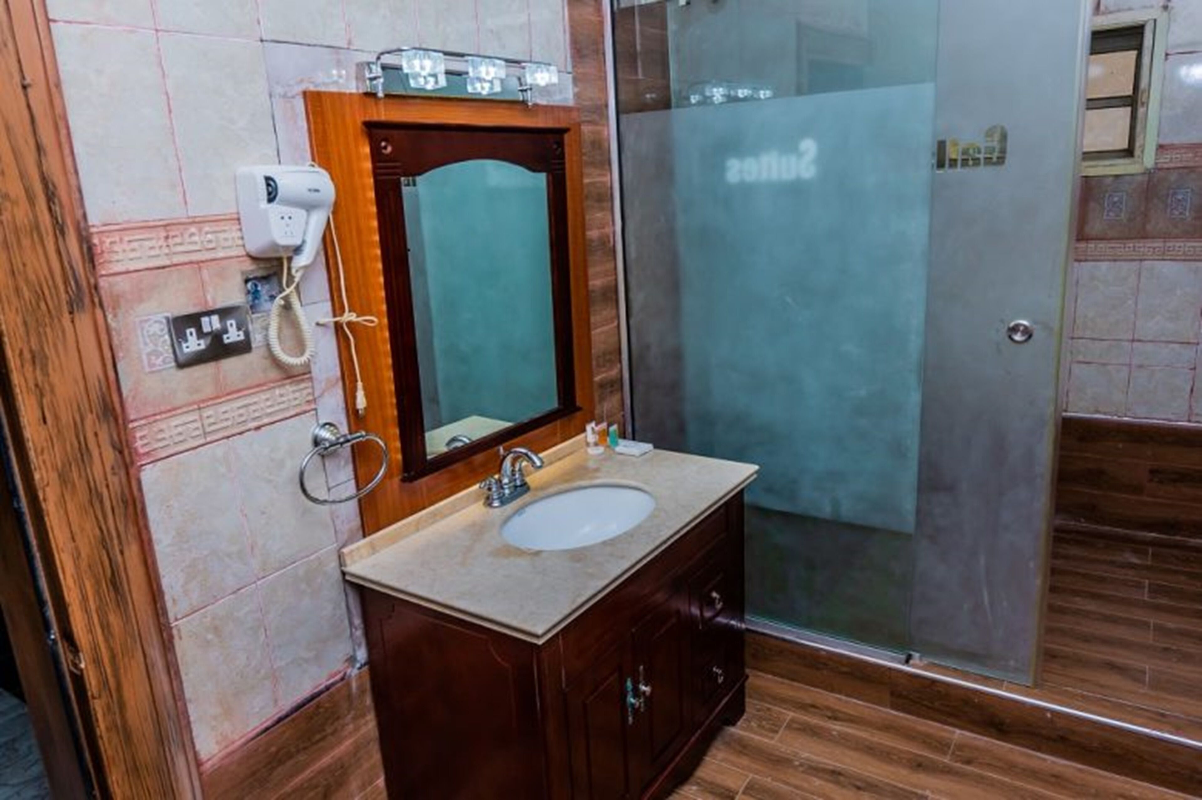 A bathroom with a wooden vanity, a mirror, a sink, and a glass shower enclosure.