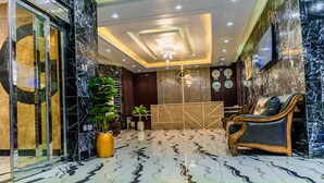 Eine Lobby mit Marmorboden, einer Rezeption, einer Couch und einer Chandelier.