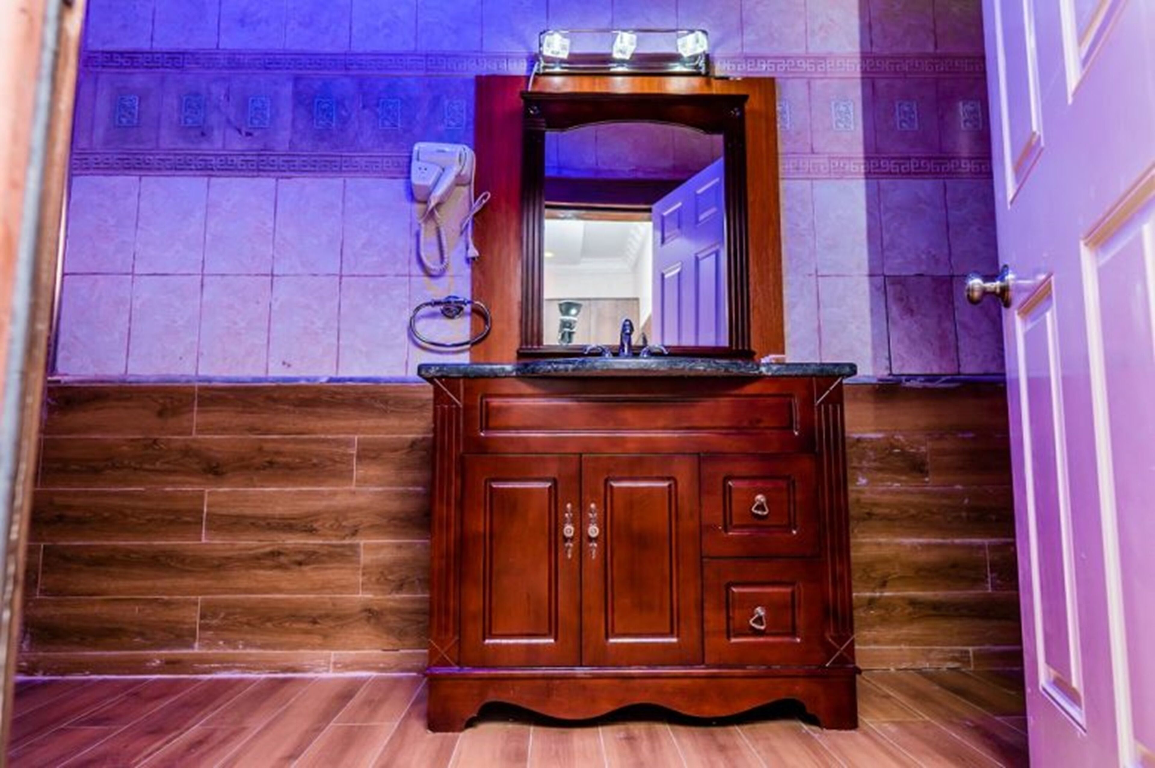 Een badkamer met een houten wastafelmeubel, een spiegel en een handdoekrek.