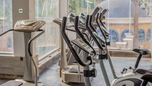 Eine Reihe von Ergometer-Trainern in einem Fitnessstudio mit großem Fenster im Hintergrund.