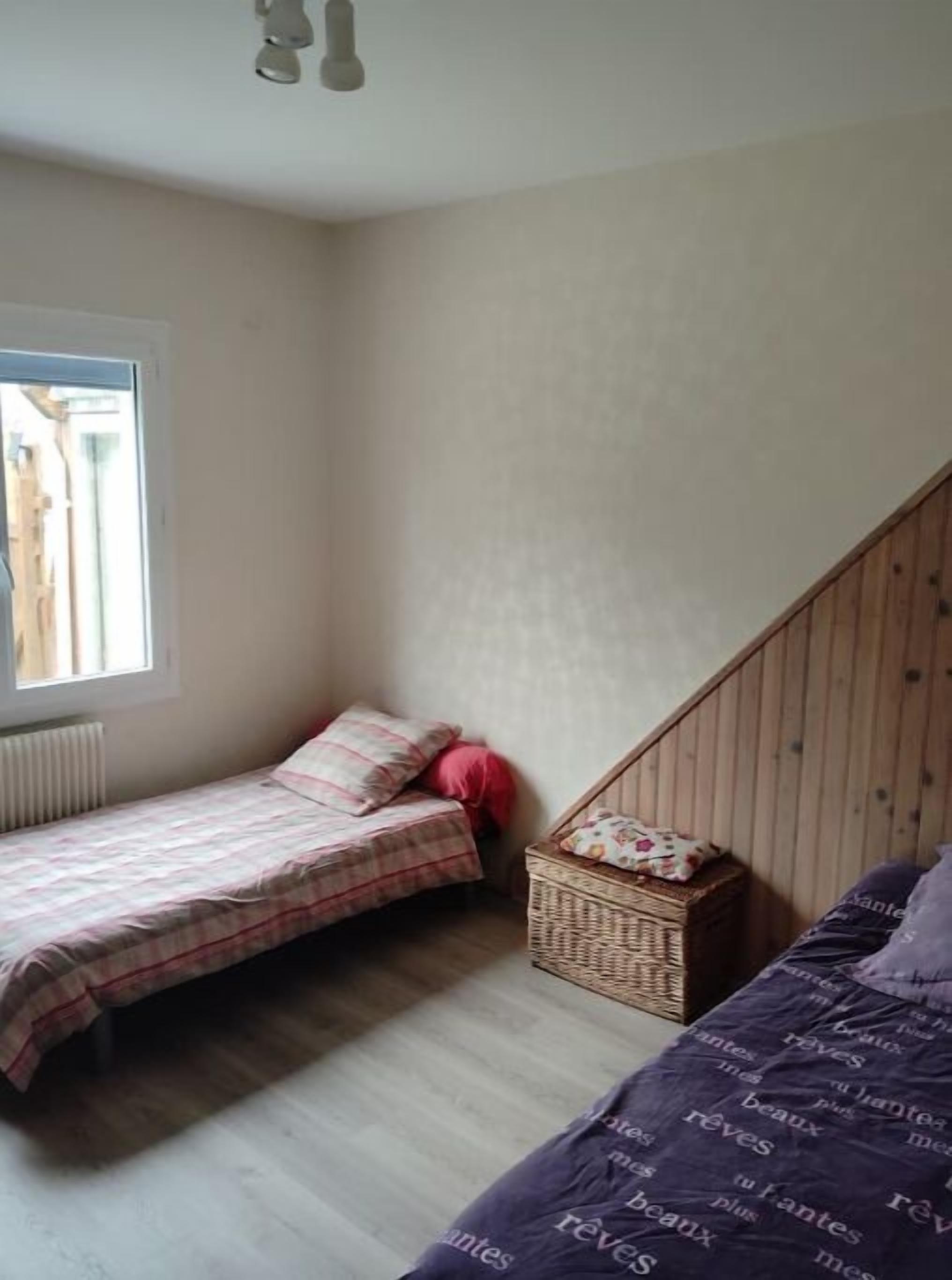 A bedroom with a bed, a small wooden chest, and a window.
