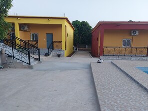 Two homes with air conditioning units, a staircase, and a paved ground.