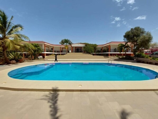 Relax by the central pool surrounded by lush greenery and palm trees.