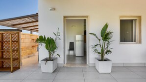 A modern building with a clean, white exterior, a covered outdoor area with a wooden fence, and potted plants. - 3771 Villino Cento Passi by Barbarhouse (Nardò)