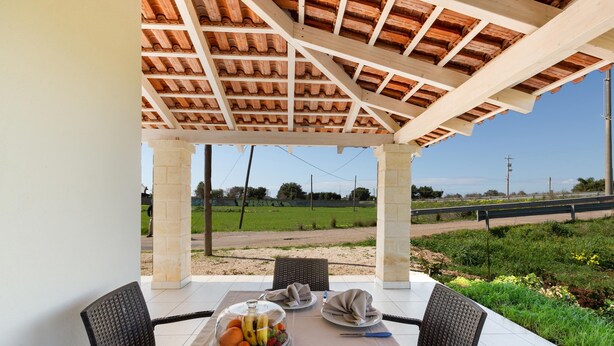 A covered patio with a table set for two, featuring a fruit bowl and a bottle. - 3771 Villino Cento Passi by Barbarhouse (Nardò)
