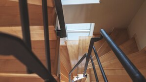 A wooden staircase with metal railings and a skylight at the top.