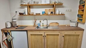 Una cuina compacta amb armaris de fusta, una aixeta integrada, una cafetera i una torradora.