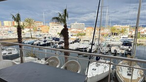 A balcony with a table and chairs overlooking a marina with various boats. - Agi Port Canigo 130 Apartamento for rent in Roses Girona. (Roses)