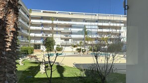 A multi-story building with balconies, a swimming pool, and a garden area with trees and a statue. - Agi Port Canigo 206 Apartamento for rent in Roses Girona. (Roses)