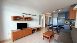 A modern living room with a flat-screen TV, wooden entertainment unit, and a grey sofa. - Agi Port Canigo 206 Apartamento for rent in Roses Girona. (Roses)