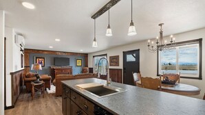 A kitchen with a large island, wooden cabinets, and a built-in dishwasher. - Family Friendly Cabins w/ Mountain & Wildlife View (Kalispell)