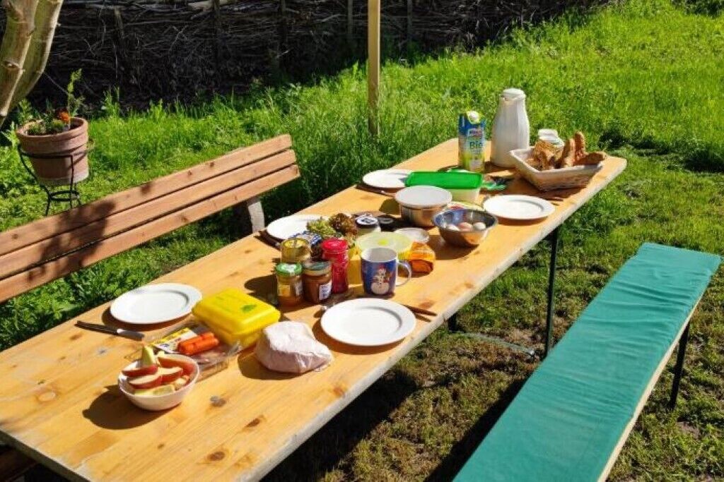 Un juego de mesa de picnic de madera al aire libre con varios alimentos y condimentos.