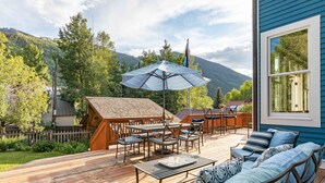 A wooden deck with outdoor furniture, a table, and an umbrella.