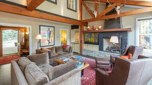 A spacious living room with a fireplace, wooden beams, and comfortable seating.