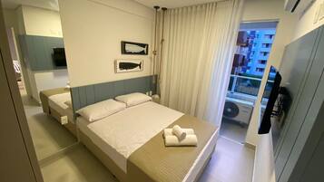 Ein Hotelzimmer mit Bett, einem großen Spiegel, einem Fenster mit Vorhängen und Blick auf Gebäude.