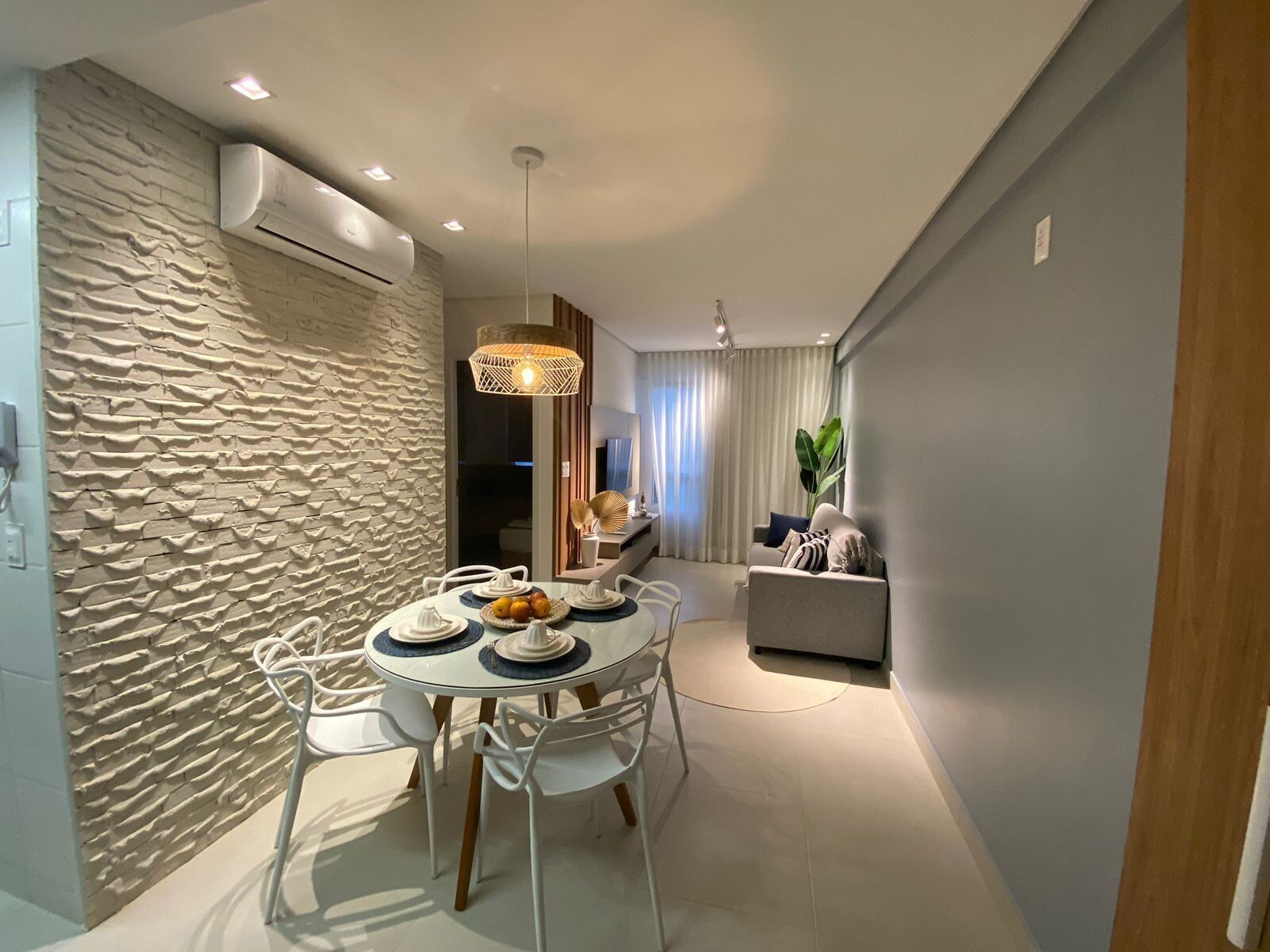 Un comedor moderno con una mesa redonda, sillas blancas y una pared con textura.