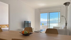 A modern hotel room with a large dining table, a TV, and a balcony with a view of the sea. - Agi Europa 62 Apartamento for rent in Roses Girona. (Roses)