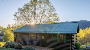 Eine Blockhütte mit Metalldach, einer Veranda und einem kleinen Garten.