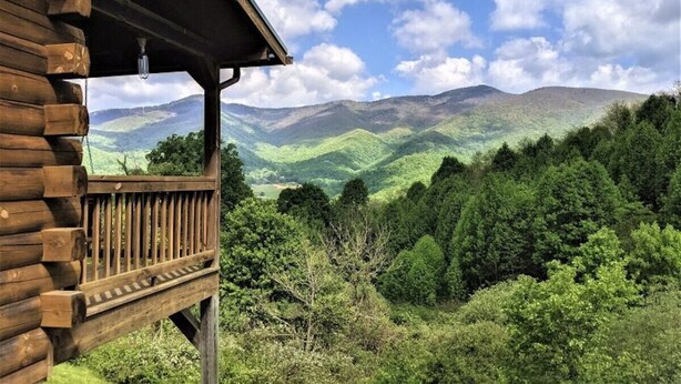 Eine Holzhütte mit Balkon mit Blick auf eine gebirgige Landschaft.