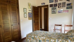 A bedroom with two beds, wooden wardrobe, and a wall decorated with various signs and pictures. - Short description of the property (San Juan de Duz)