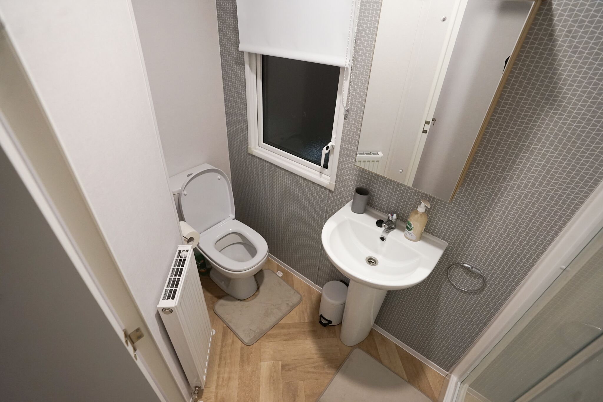 Une petite salle de bain comprenant des toilettes, un lavabo et une fenêtre.