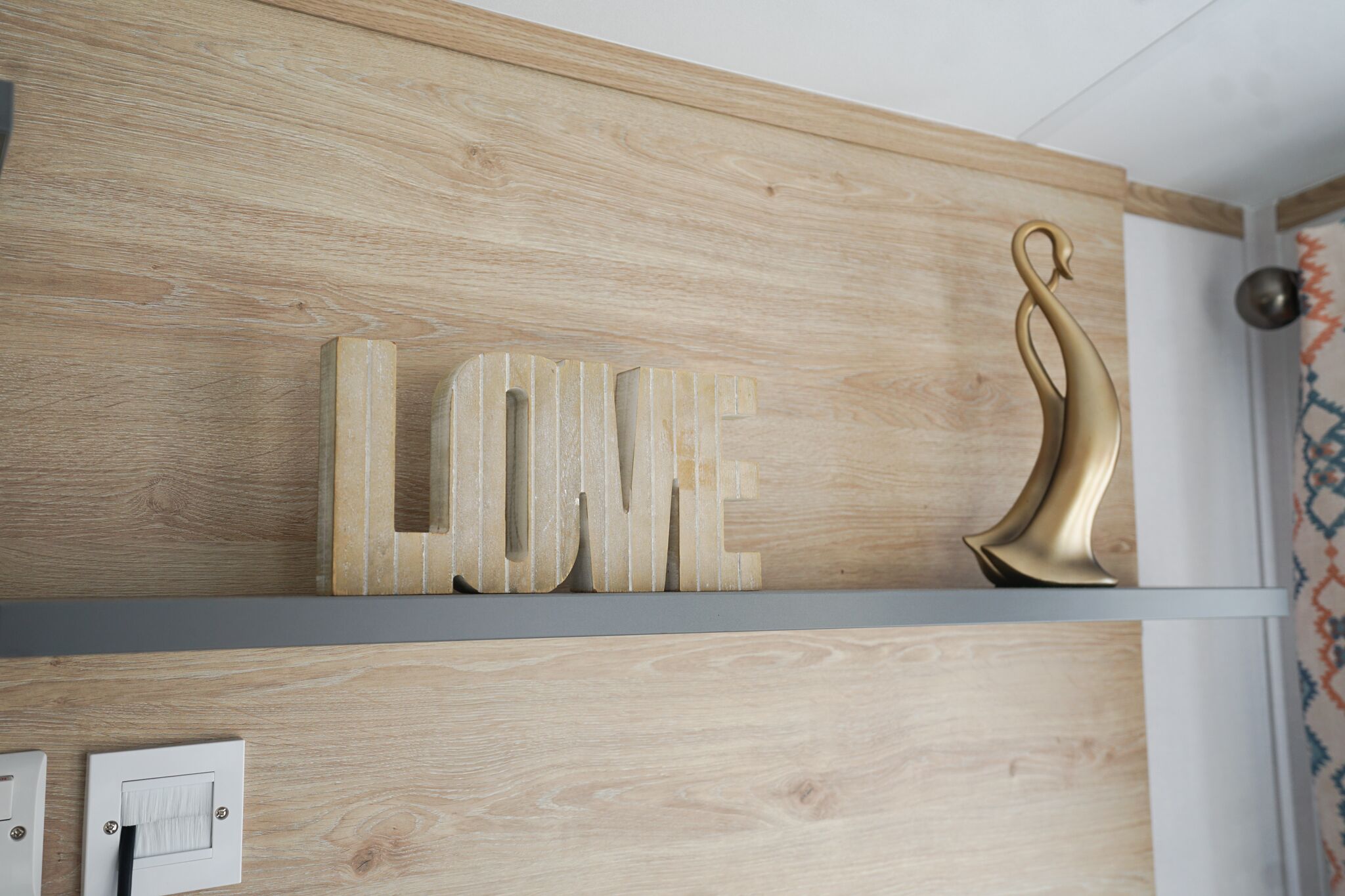 A wooden wall with the word "LOVE" and a golden swan decoration.
