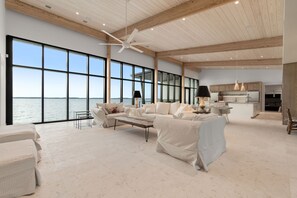 A spacious living area with large windows, a ceiling fan, and a view of the water.