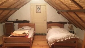 A small attic bedroom with two wooden beds, a door with a butterfly decoration, and a wooden ceiling. - Gite à la Campagne (Quins)