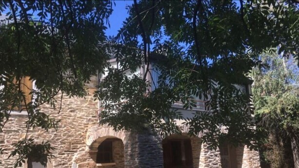 A stone building with arched doorways and a small wooden bench outside. - Gite à la Campagne (Quins)
