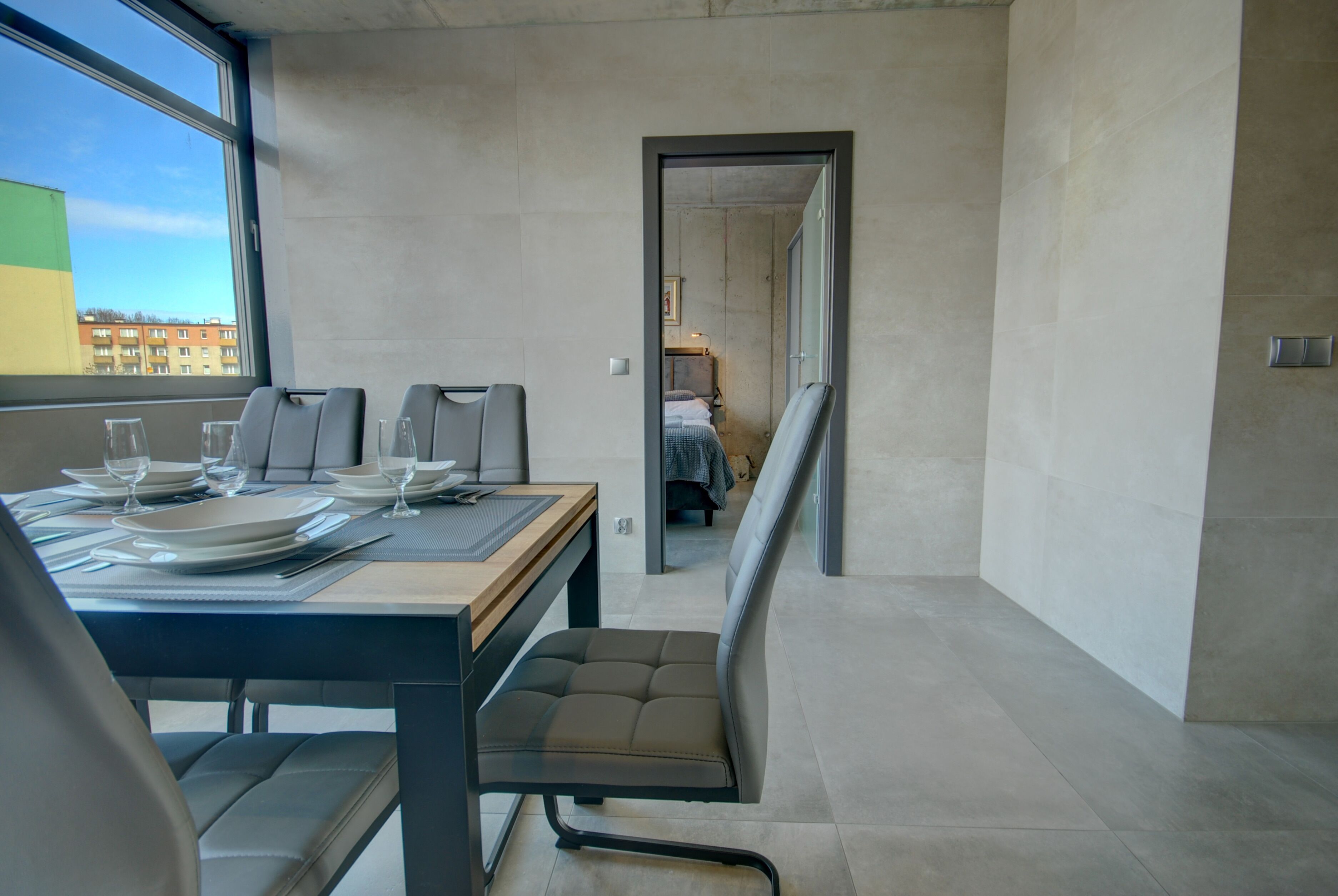 Une chambre d’hôtel moderne dotée d’un coin repas, d’un lit et offrant une vue sur le paysage urbain.