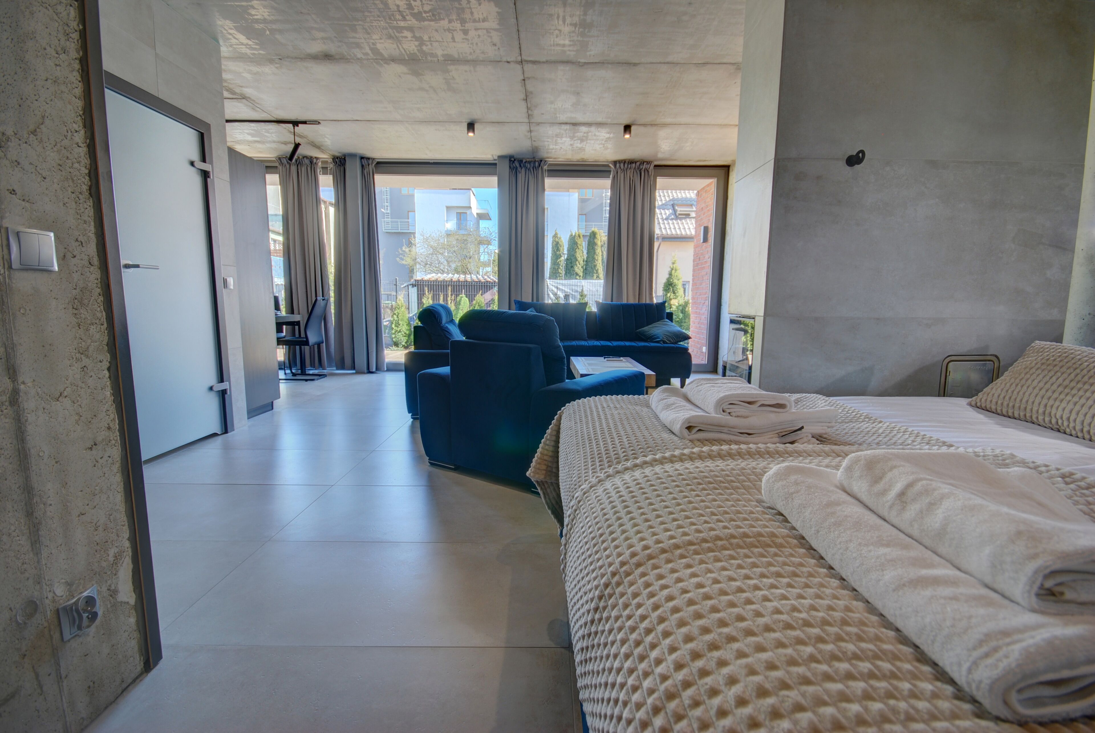 Una habitación de hotel moderna con una cama grande, un sofá y un balcón con vistas a la ciudad.