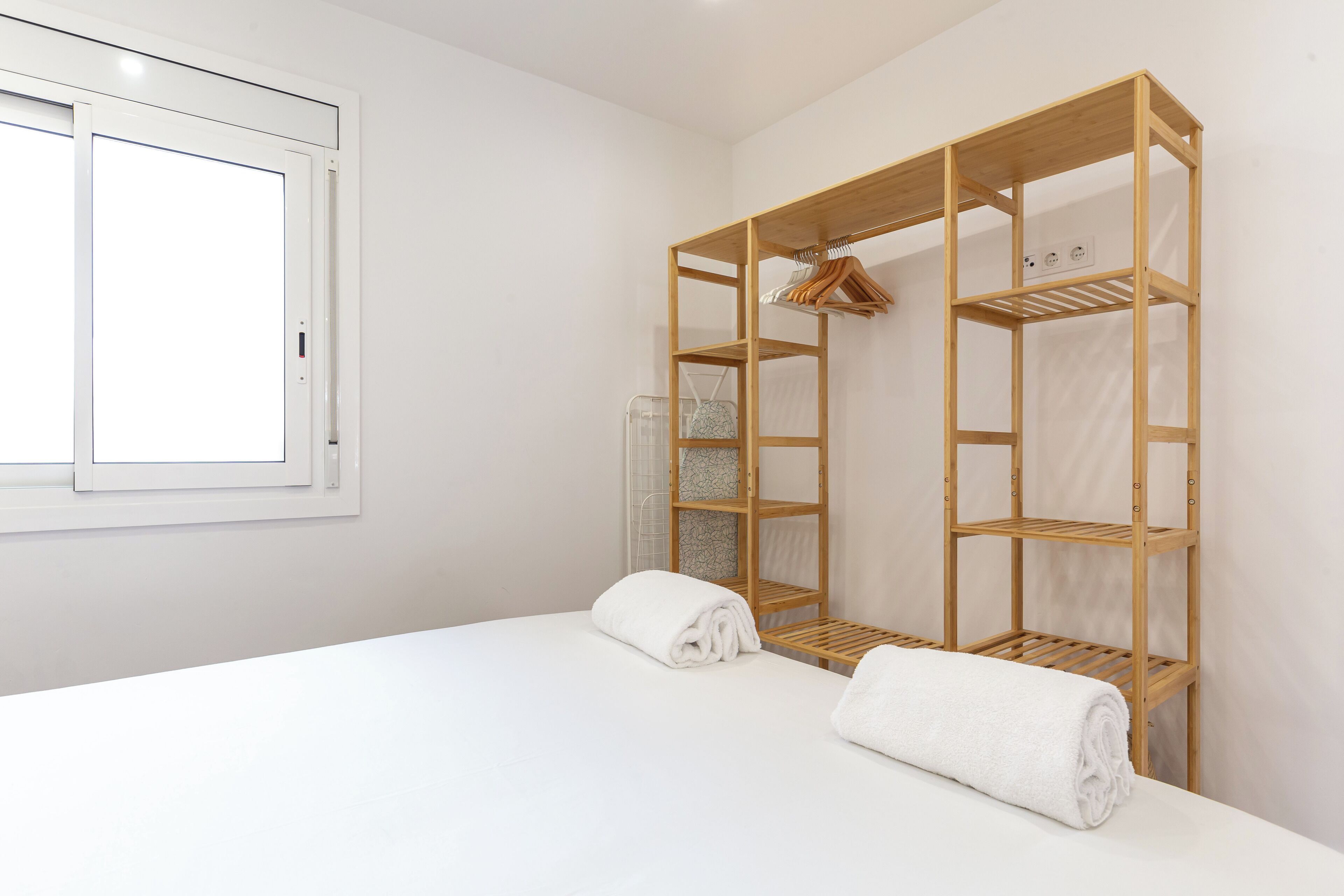A hotel room with a bed, a wooden wardrobe, and a window.