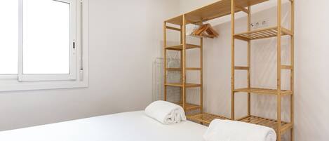A hotel room with a bed, a wooden wardrobe, and a window.