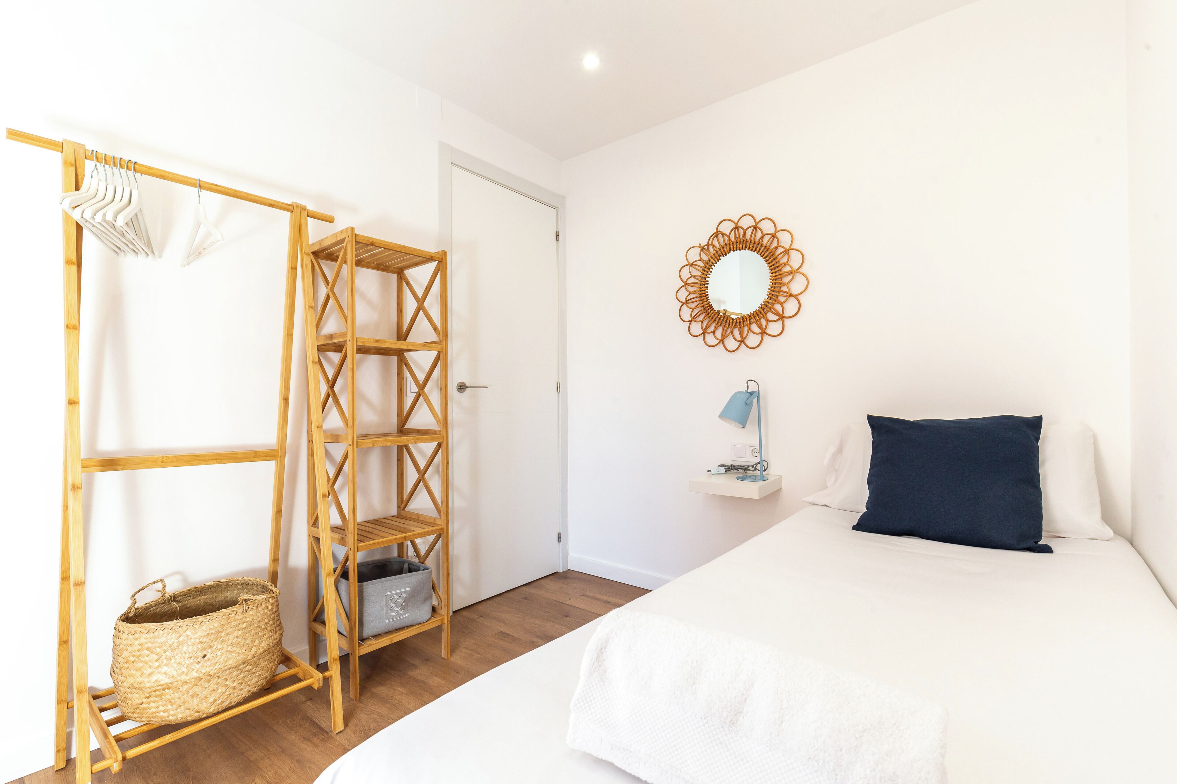 Un dormitorio con cama, armario de madera, espejo y estante en la pared.