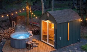 Un jacuzzi, una terraza de madera y un cobertizo pequeño con puerta de vidrio.