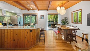 Eine moderne Küche mit Holzschränken, einer zentralen Kochinsel und einem Essbereich mit Holztisch und Stühlen.